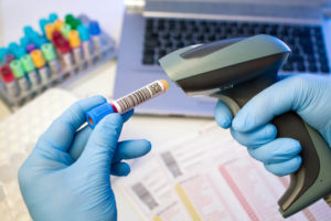 Technician hands scanning barcodes on biological sample tube in the lab of blood bank